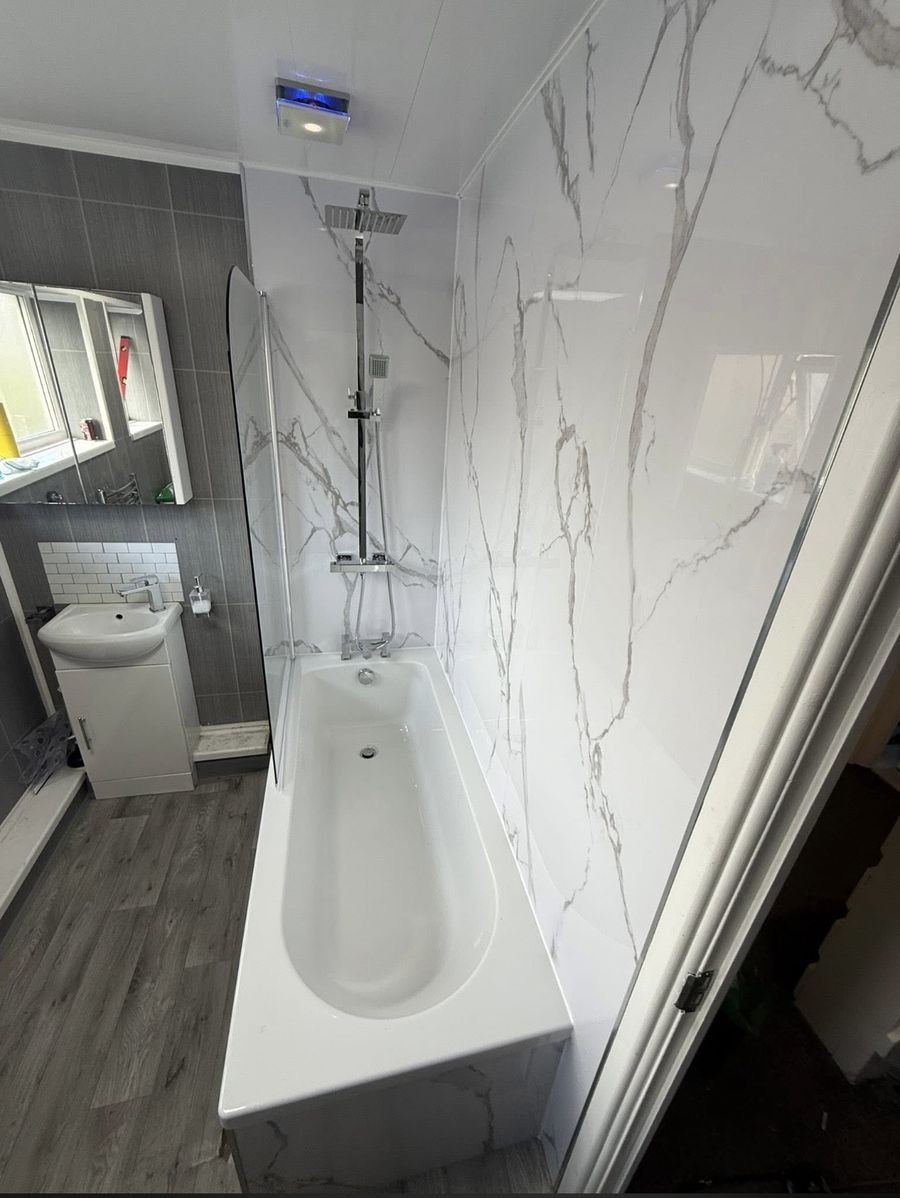 Bathroom after the work — marble-effect panels with new bath and shower