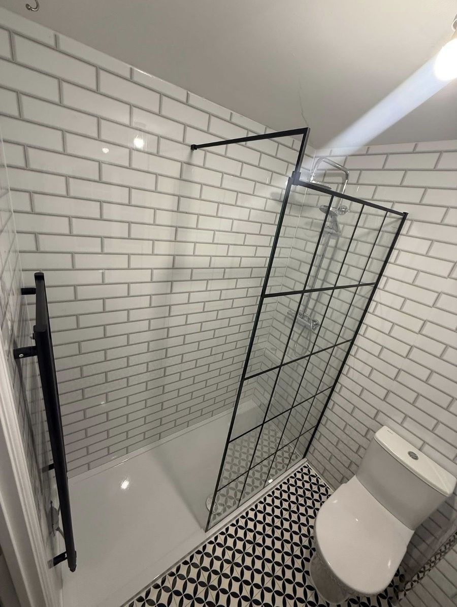 Bathroom after the work — white brick tiling with black-framed shower screen