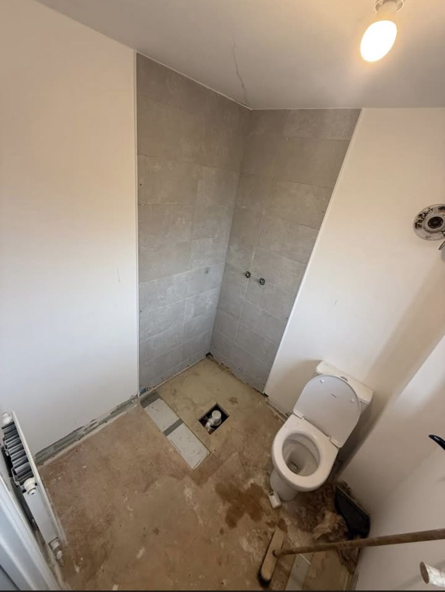 Bathroom before the work — bare plaster and old fittings