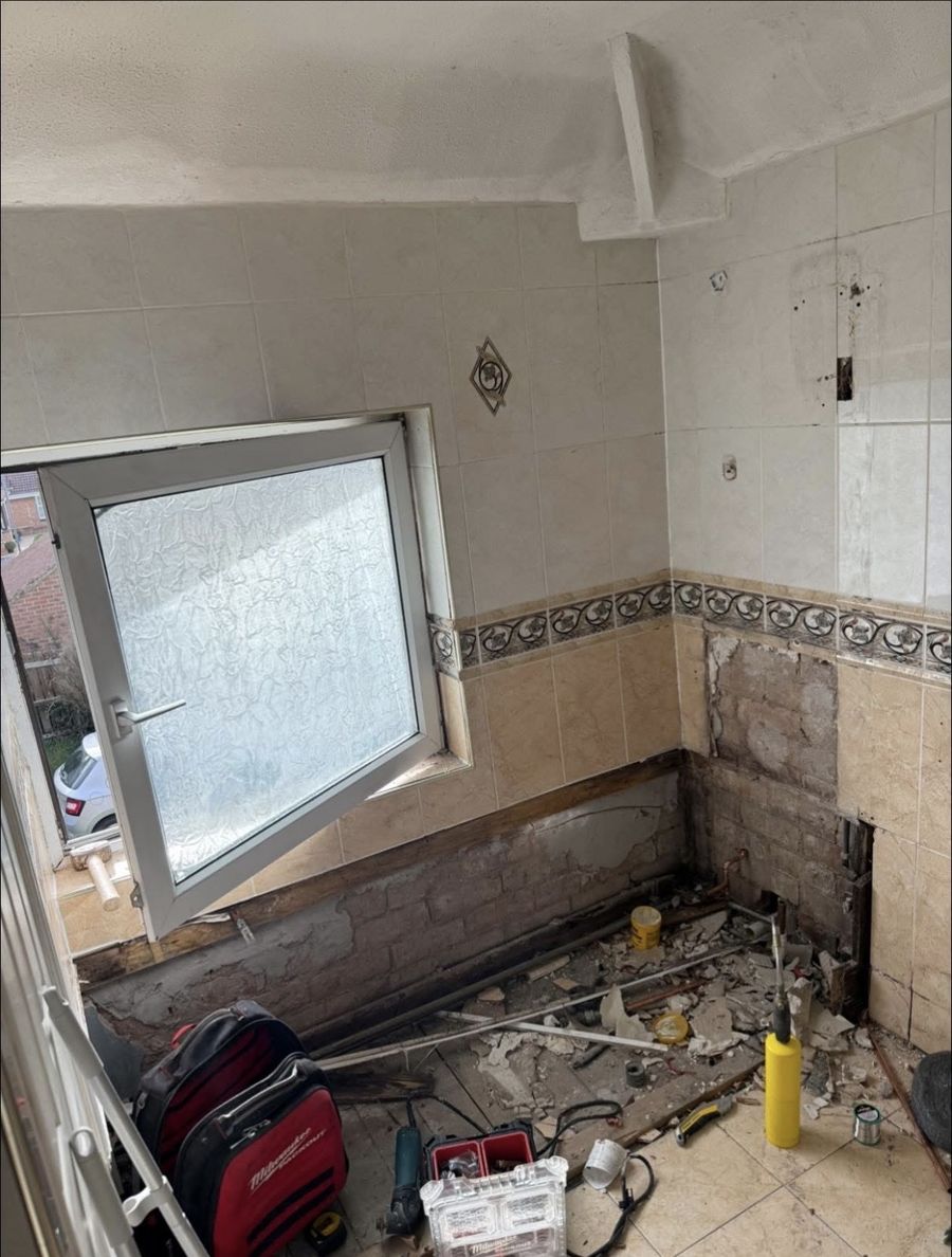 Bathroom before the work — old tiles removed and walls stripped back