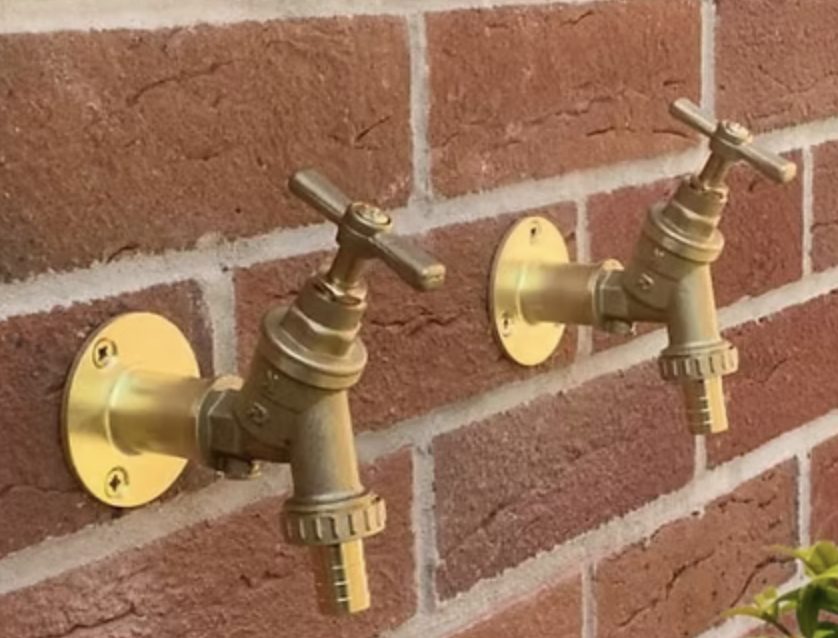 Two brass outside taps fitted on a brick wall by Jacob Conway Plumbing Services